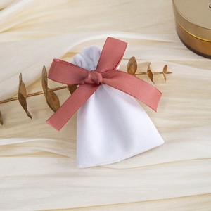 Close-up of a soft white velvet drawstring jewelry pouch with a brown ribbon bow
