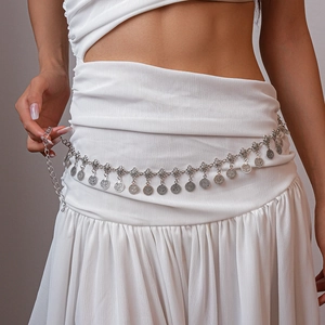Detail of vintage silver metal waist chain with flower coins on a white dress