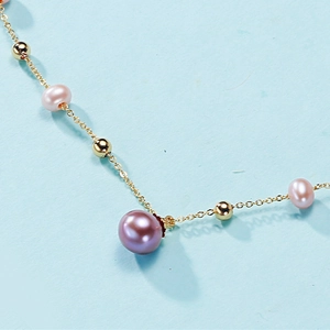Elegant gold necklace with multi-colored freshwater pearls and gold beads on a blue surface