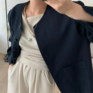 Close-up of a large silver bead pendant necklace on a navy tweed jacket and cream top