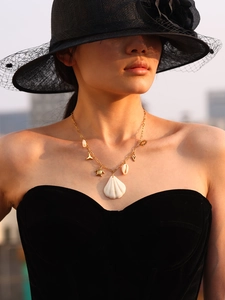 Detail of a golden ocean necklace with sea turtle and shell pendants on a model
