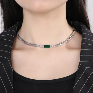 Detail of silver Cuban chain necklace with green square emerald pendant on model