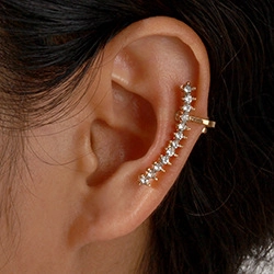 Close-up of gold ear cuff with clear cubic zirconia on a model with black hair