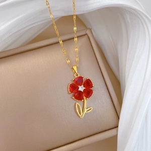 Detail view of a gold floral necklace with red ruby petals and crystal center on jewelry box
