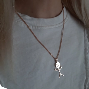 Funny doodle matchman necklace in rose gold finish worn on female model's neck