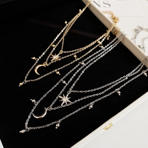 Close-up of gold and silver layered necklaces with star and moon charms in a gift box