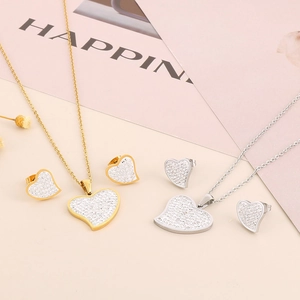 Close-up of gold and silver heart-shaped pendant necklace and stud earrings set with rhinestones