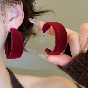 Détail montrant des créoles en velours rouge foncé en forme de C sur un modèle