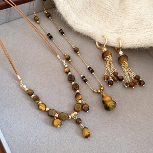Macro shot of tiger eye stone jewelry set with tassel earrings on a velvet tray
