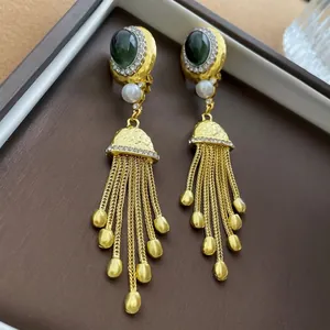 Boucles d'oreilles vintage dorées avec pierres vertes et perles sur boîte à bijoux brune