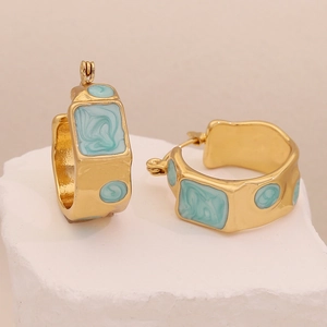 Detail of gold-plated geometric earrings with blue marble enamel on a stone base