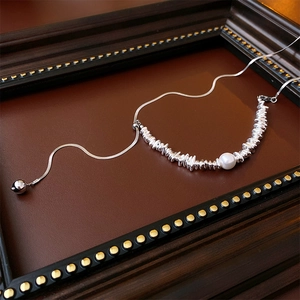 Detail of baroque pearl necklace with silver irregular beads and snake chain in vintage frame