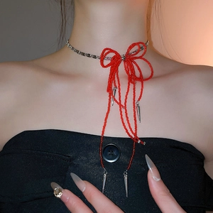 Close-up of red beaded bow necklace with silver metal spikes on a female model
