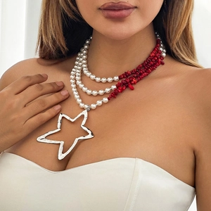 Detail of layered pearl and red stone necklace with a large hammered silver star pendant