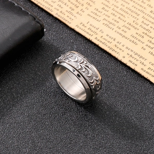 Close-up of vintage wide titanium steel ring with intricate floral engraving on black leather