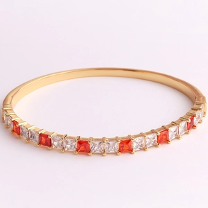 Macro detail of 18K gold plated bangle with red and white square-cut zircon stones