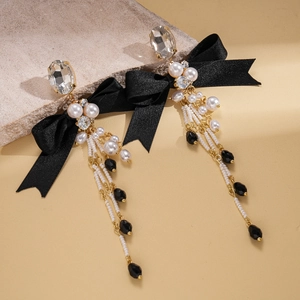 Detailed view of elegant black ribbon bow earrings with pearls and diamond tassels