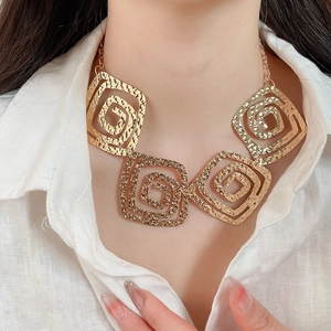 Detail of model wearing gold necklace with four hammered textured spiral square pendants