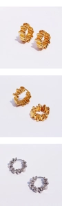 Detail shot of wavy texture earrings in gold and silver finish on white background