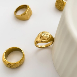 Detail of vintage gold rings set with embossed Medusa pattern and hammered texture