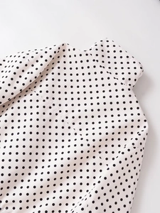 Detalle de camisa blanca con lunares negros y acabado de costura de alta calidad