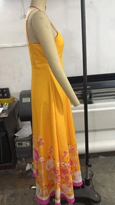 Detail of a long yellow halter dress featuring elegant pink and white floral patterns