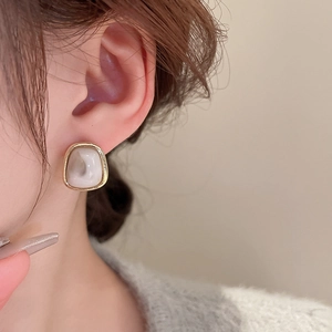 Detail of vintage geometric earrings with gold frame and marble resin worn by a model