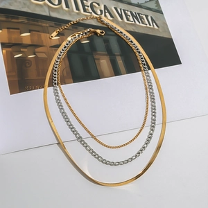Detailed macro view of triple-layered mixed metal necklaces with flat snake and cable chains