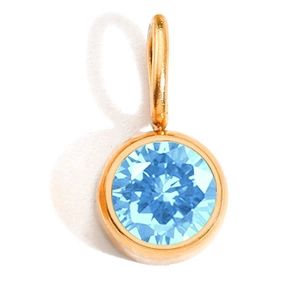 Macro shot of light blue birthstone pendant with round faceted cut in gold metal frame