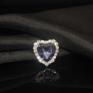 Macro shot of heart-shaped blue crystal with silver claw setting on black silk background