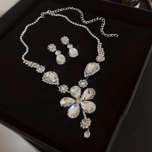 Macro view of crystal floral necklace and teardrop earrings in a black gift box