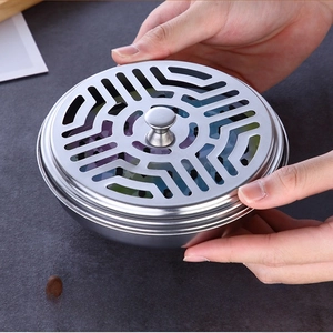 Detail of round stainless steel mosquito coil holder with geometric hollow lid and smooth edges