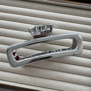 Detailed view of silver metallic shark hair clip on a beige textured jewelry tray