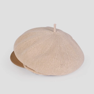 Détail de la casquette gavroche en maille beige avec visière brune et texture tricotée