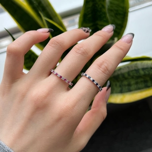 Macro shot of S925 sterling silver eternity rings with red and blue gemstones on finger