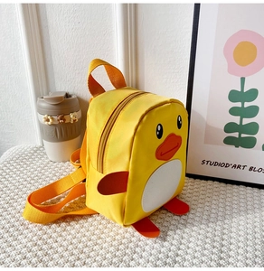 Cute yellow duck toddler backpack with orange straps on a cozy woven mat display