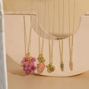 Detailed shot of fruit and wing pendants with zircon accents on gold necklaces