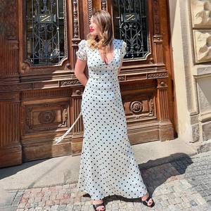 Détail de la robe maxi blanche à pois avec col en V et manches bouffantes au soleil