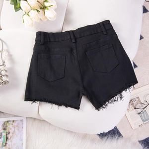 Dettaglio di pantaloncini in denim nero con orli sfilacciati su sfondo bianco morbido