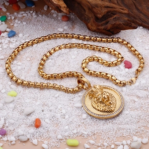 Golden lion head medallion pendant necklace with crystal edge on decorative white pebbles