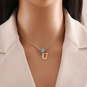 Detail of gold letter U pendant with blue evil eye bead on a twisted chain necklace