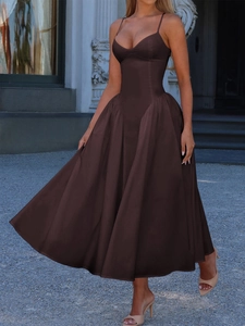 Elegant woman in brown sleeveless maxi dress standing on stone steps outdoors