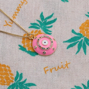 Dettaglio del ciondolo Evil Eye in smalto rosa con cristalli colorati e catena dorata