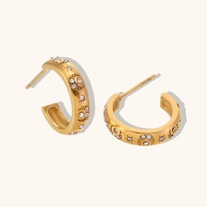 Detailed macro view of gold-plated C-shape earrings with zircon moon and star engravings