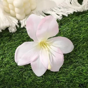 Close-up of a realistic pink lily hair clip on green grass with a cozy aesthetic