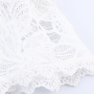 Macro view of delicate white floral lace fabric on a French style two-piece skirt set