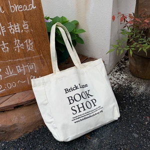 Close-up of Brick Lane Book Shop logo print on a white canvas tote bag with long handles
