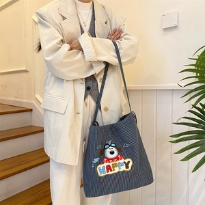 Close-up of striped canvas tote bag with happy dog embroidery and high-capacity detail