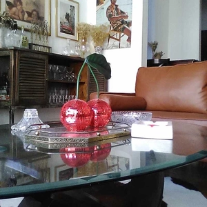 Close-up of red mosaic disco ball cherries with green leaves on a mirrored tray