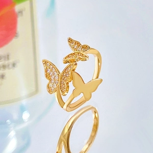 Gold triple butterfly ring with cubic zirconia crystals on a reflective surface